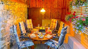 Ein rustikaler Essbereich aus Holz mit einem runden Tisch, Stühlen und einem hängenden Blumenkorb.