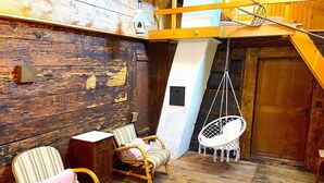 Ein rustikales Zimmer aus Holz mit zwei Korbstühlen, einem kleinen Holzschrank und einem weißen Hängesessel.