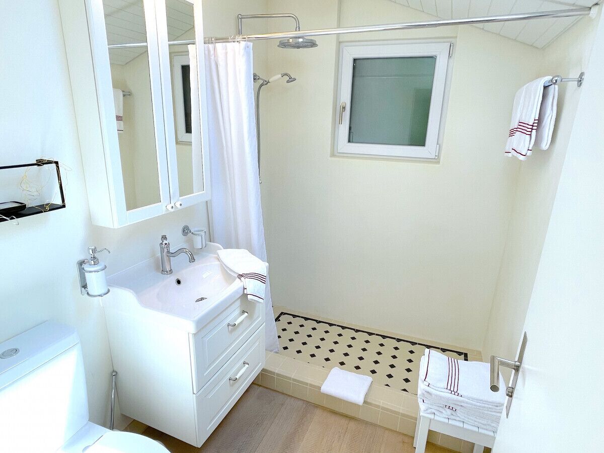Une salle de bain avec un lavabo blanc, un miroir et une douche.