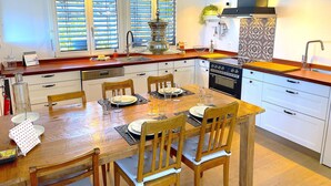 Une cuisine moderne avec des meubles blancs, une table à manger en bois et un fourneau noir.