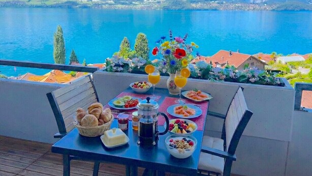 Une table dressée pour le petit-déjeuner, avec vue sur une montagne et un lac.