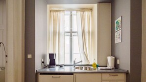 Una piccola cucina con lavello, macchina del caffè e una bottiglia di detersivo per piatti.