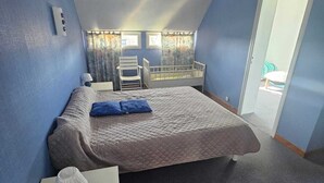 A bedroom with a bed, a small table, a chair, and a crib.
