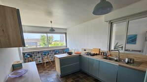 A compact kitchen with a window, a dining area, and a view of the outside.