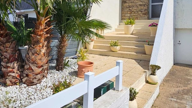 A modern building with a stone facade, a white fence, and a palm tree in the foreground.
