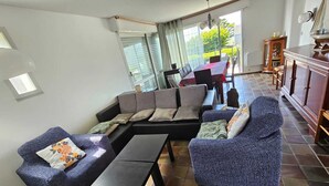 A modern living room with a sectional sofa, two armchairs, a coffee table, and a dining area with a table and chairs.