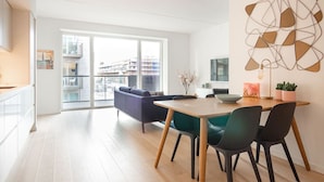 En moderne stue med spiseområde, sofa og udsigt gennem en glasdør.