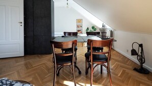 Een eethoek met een houten tafel en stoelen, een zwart kastje en een potplant.