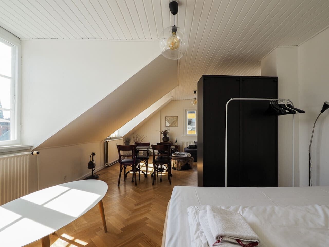 A bedroom with a bed, a desk, and a chair. There is a window and a radiator.
