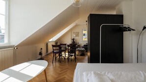 Een slaapkamer met een bed, een bureau en een stoel. Er is een raam en een radiator.