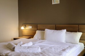 A neatly made bed with white linens and pillows, a wooden headboard, and a bedside lamp. - Hotel Horizont Telavi (Telavi)