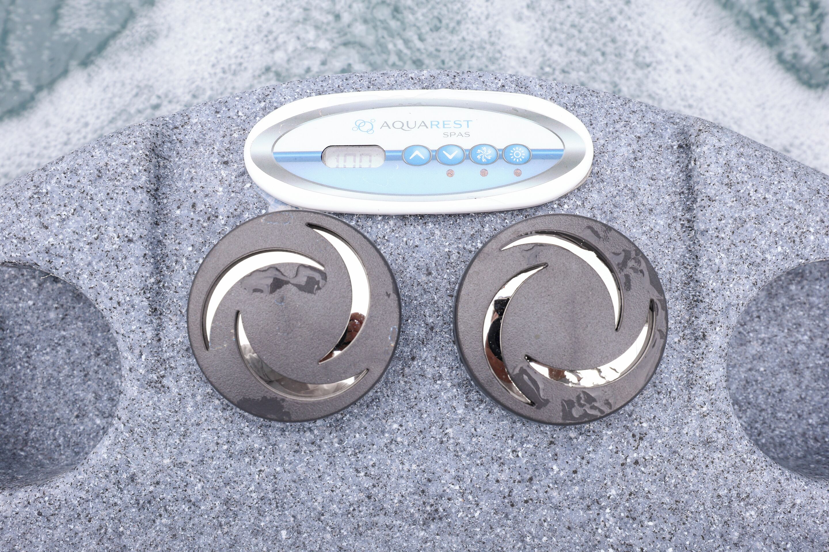 A spa control panel with two circular metallic objects on a textured surface.