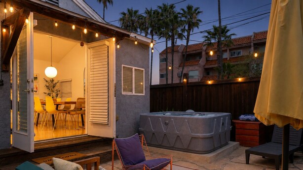 Eine Außenpatio mit Whirlpool, einem Essbereich mit Stühlen und einer Holzterrasse.