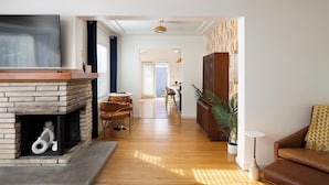 Ein Wohnzimmer mit Kamin, Fernseher, einer Couch und einem Essbereich mit Stühlen.
