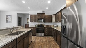 Una cocina moderna con armarios de madera oscura, electrodomésticos de acero inoxidable y encimera de granito.