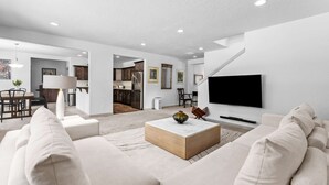 Una sala de estar moderna con un televisor de pantalla plana grande, una mesa de centro de madera y un sofá.