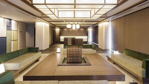 Un moderno vestíbulo de hotel con una zona de estar central, un mostrador de recepción y un amplio tragaluz.