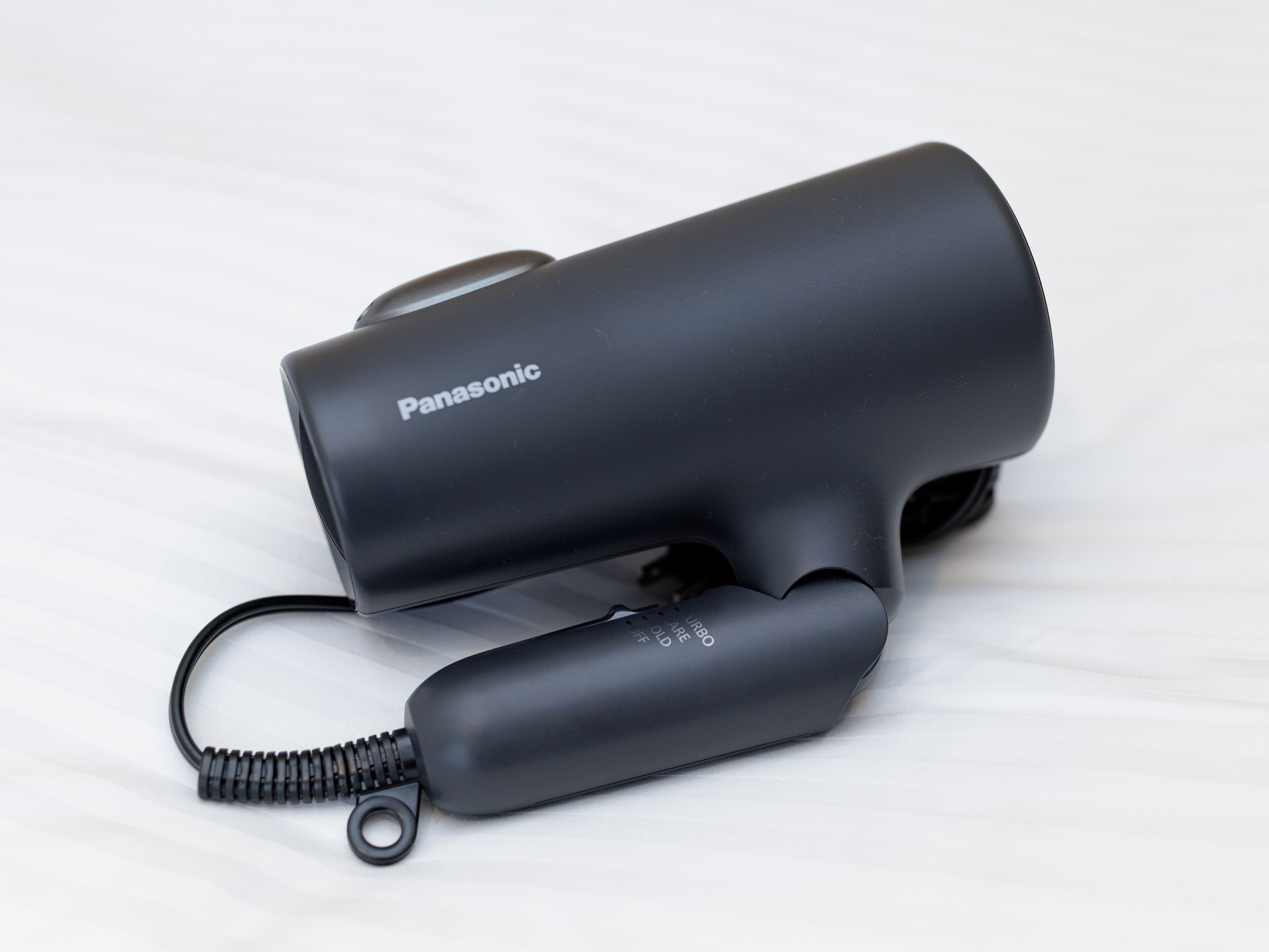 Un secador de pelo Panasonic con cable y un adaptador de corriente.