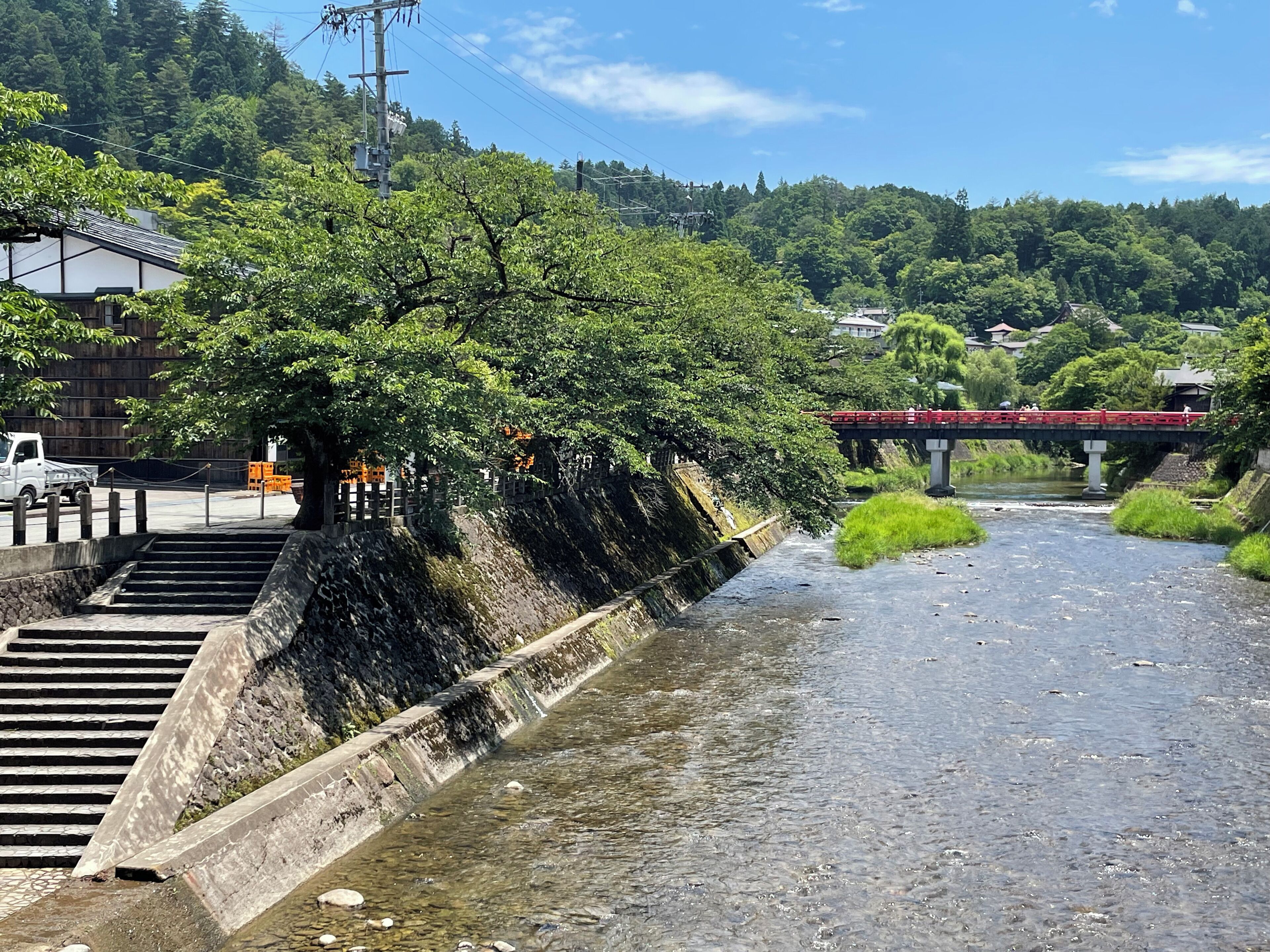 A river with a stone embankment and a red bridge in the background.