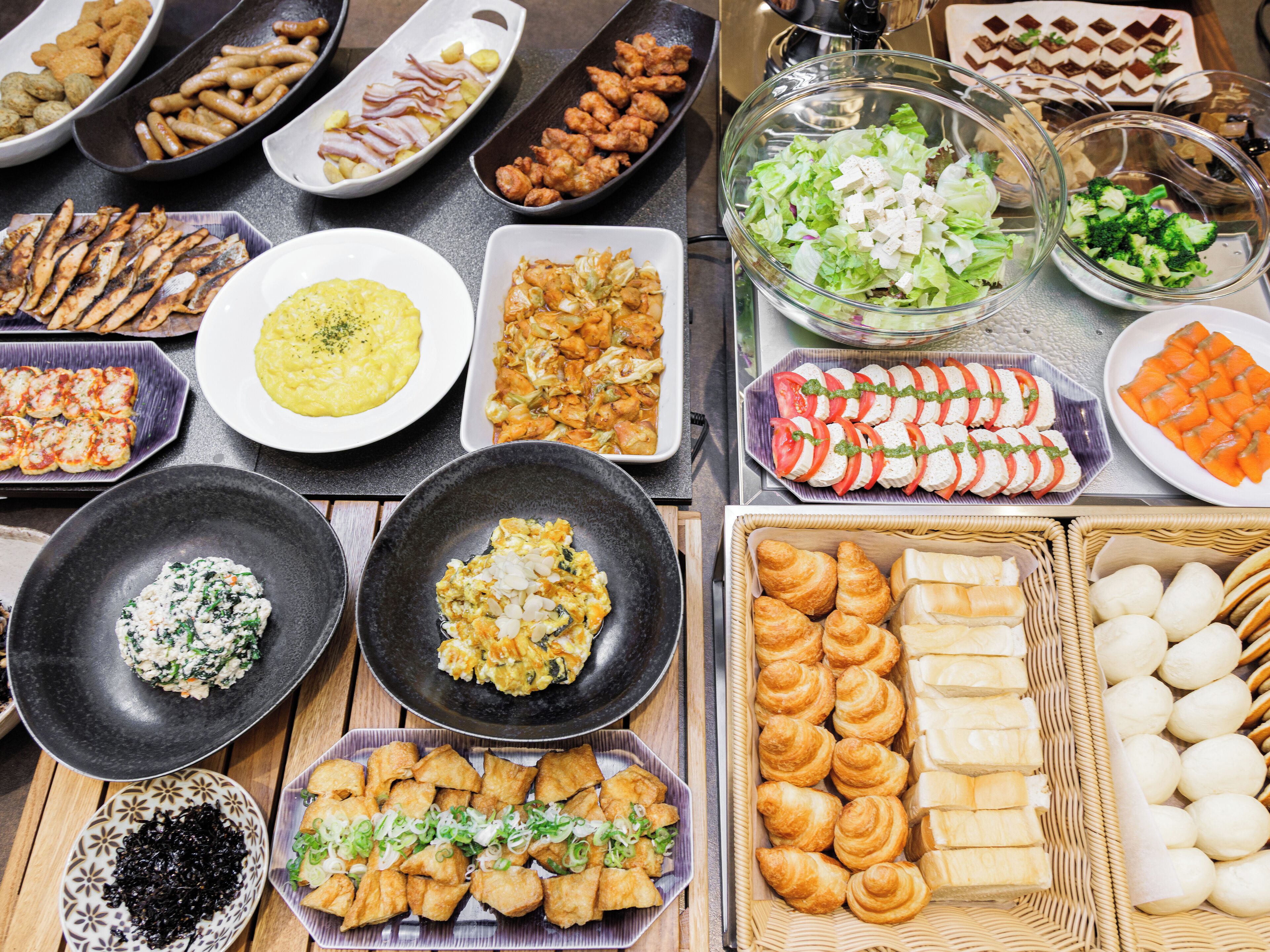A variety of food items including sushi, croissants, and other pastries arranged on a table.