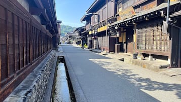 A narrow street with traditional wooden buildings, a stone water channel, and a clear sky.