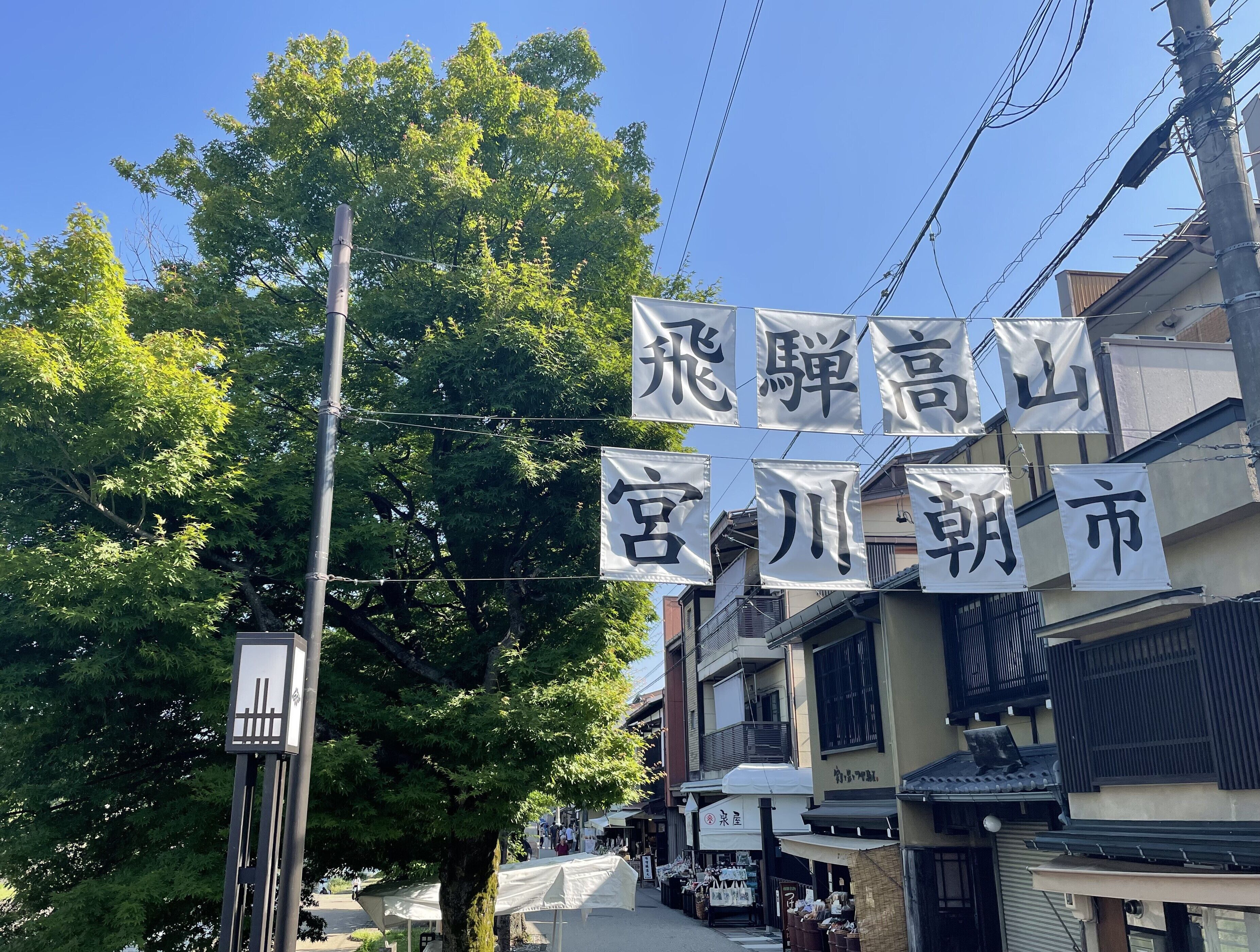 A street with traditional Japanese buildings, banners with Japanese characters, and a clear blue sky.