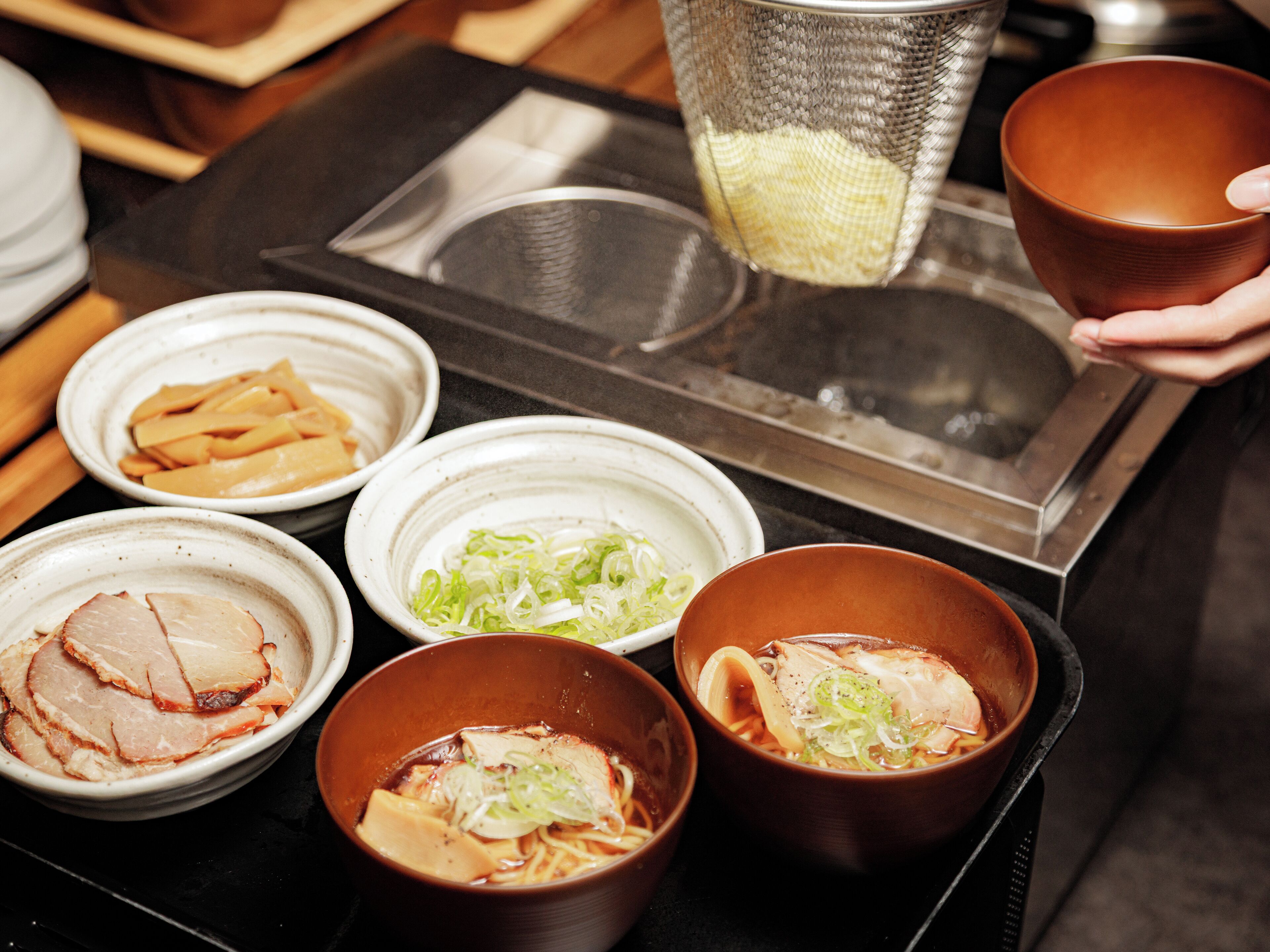 Una mesa con varios cuencos de comida, incluyendo ramen y otros platos.