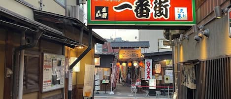 Una calle estrecha con arquitectura japonesa tradicional, que incluye edificios de madera y señalización en japonés.