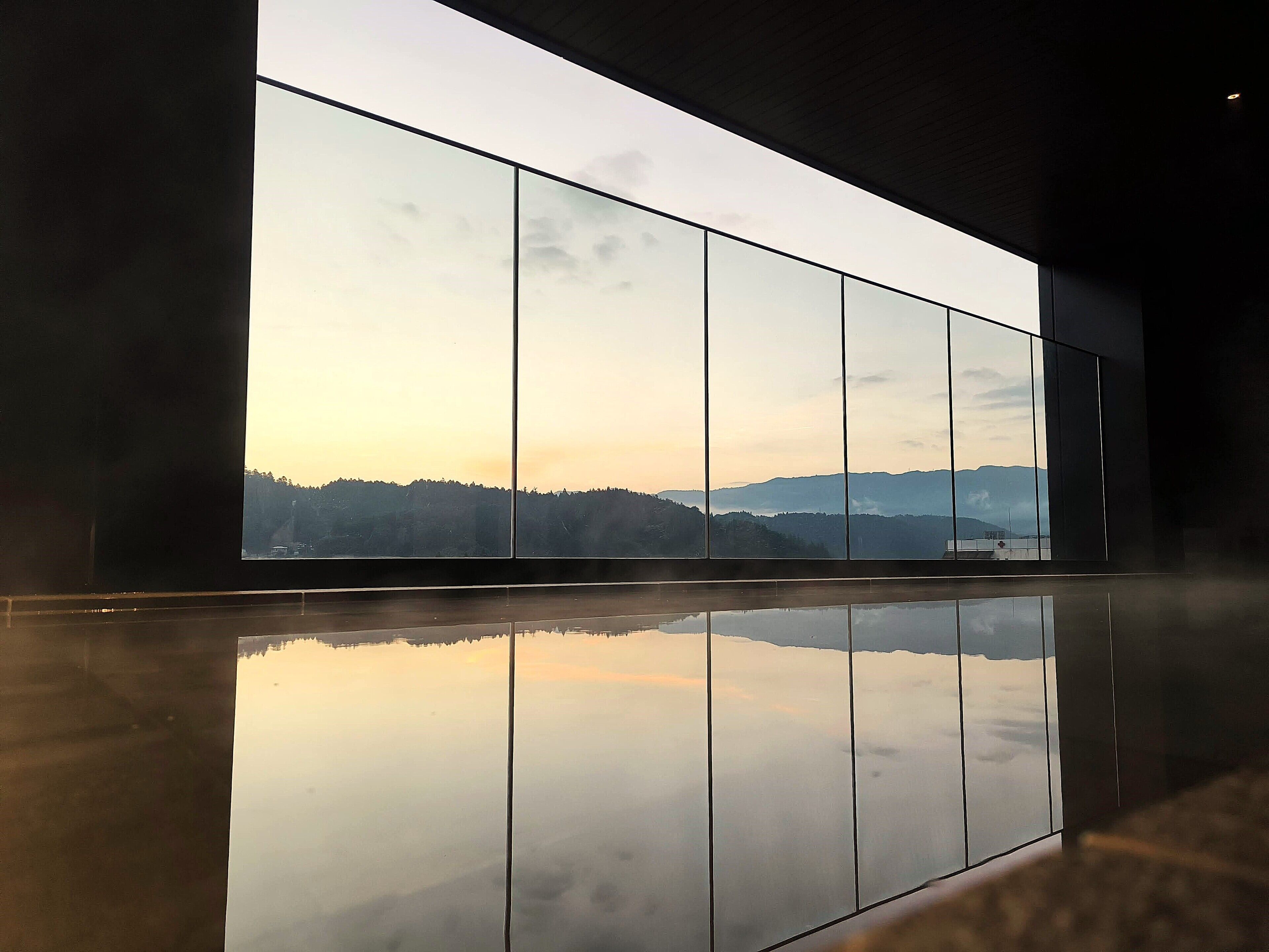 A modern interior with a large window reflecting a mountainous landscape.