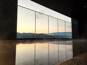 A modern interior with a large window reflecting a mountainous landscape. - HOTEL AMANEK HidaTakayama (Takayama)