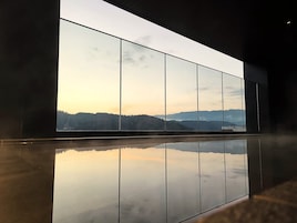 Un interior moderno con un amplio ventanal que refleja un paisaje montañoso.