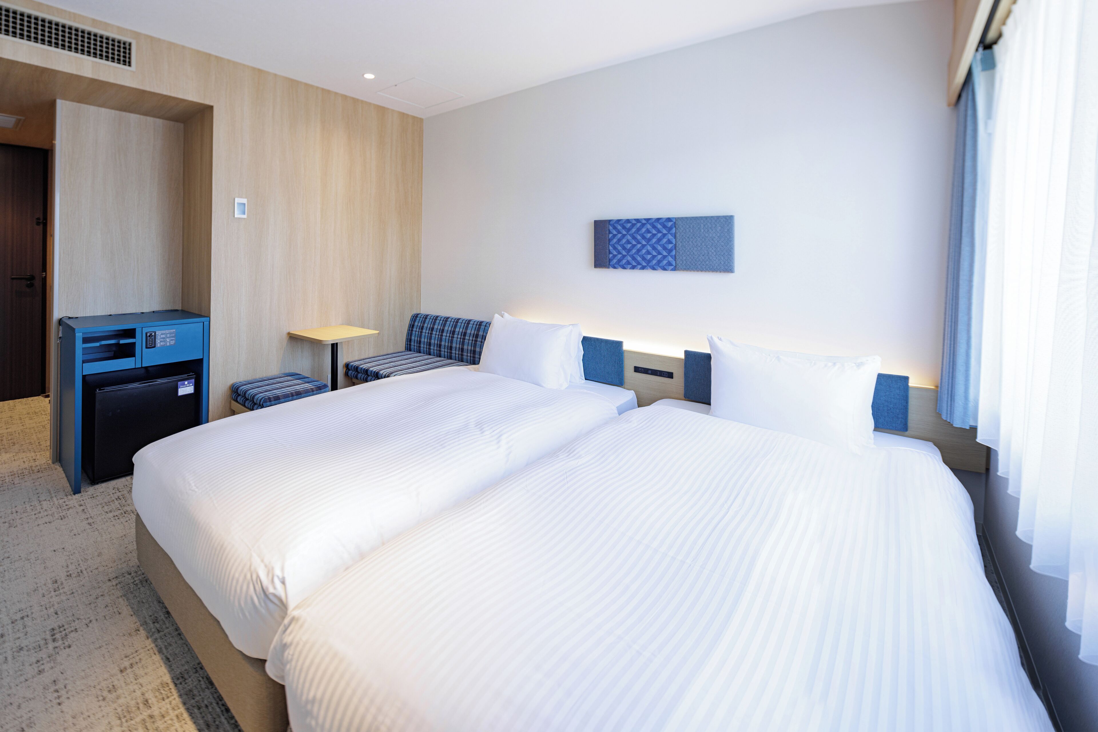 A hotel room with a large bed, a desk, a chair, and a small table.