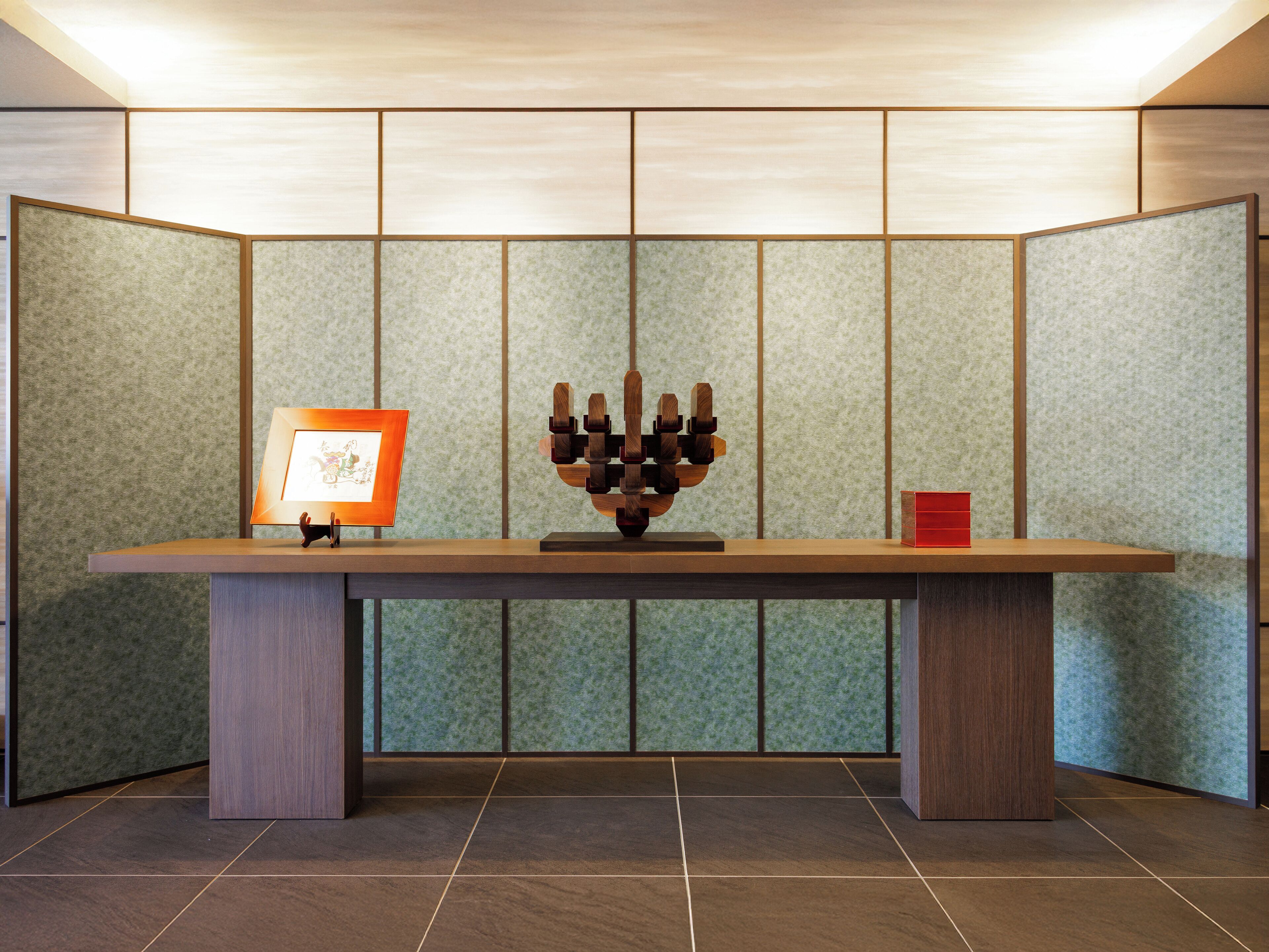 A reception desk with a framed picture, a wooden sculpture, and a red box.