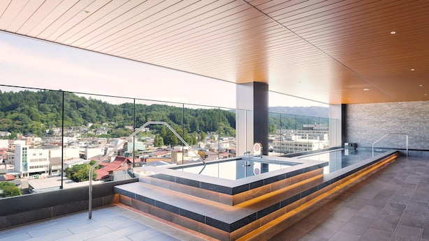 Un interior moderno con balcón de vidrio, una zona de asientos escalonada y vistas a un paisaje urbano.