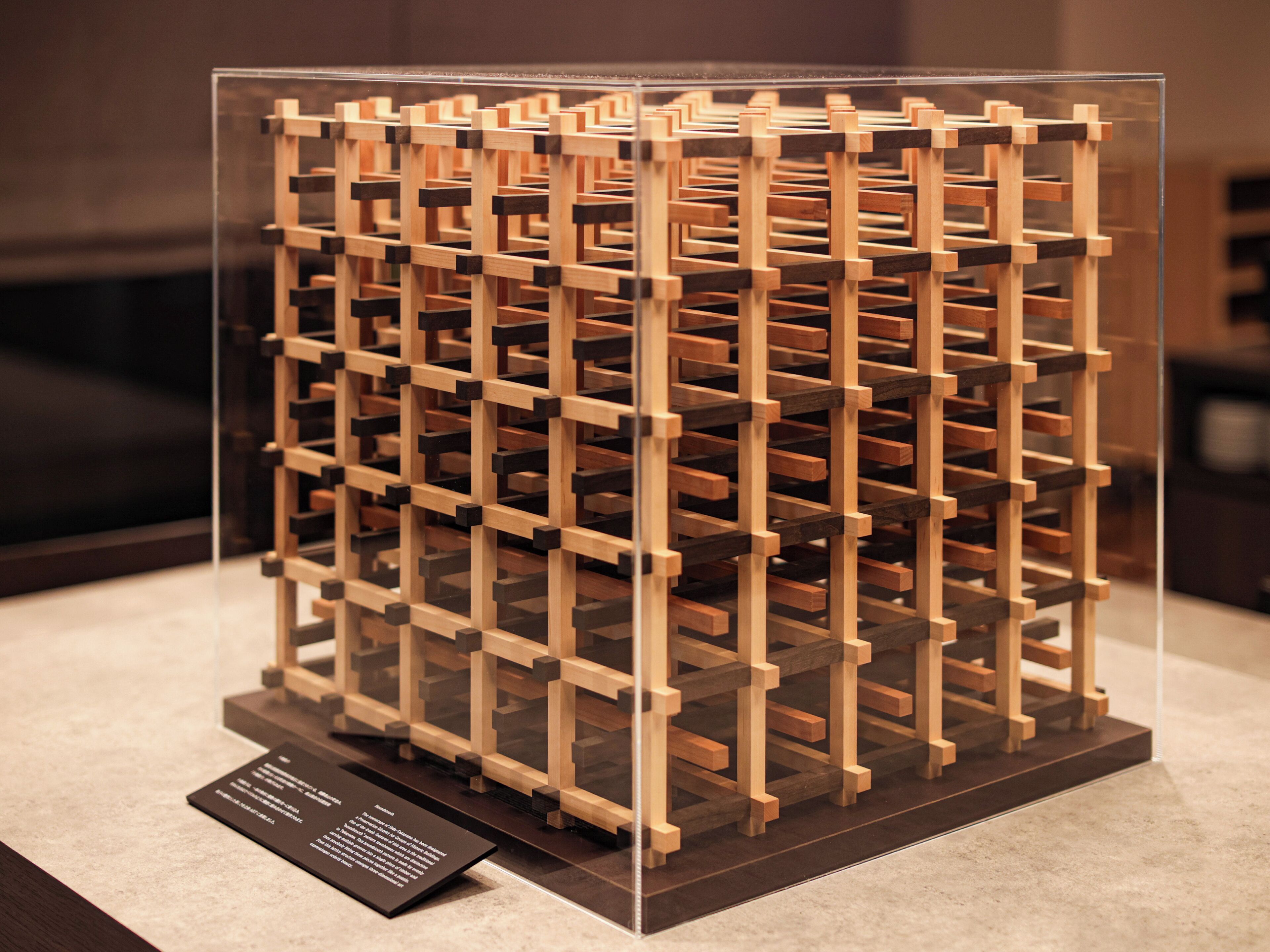 Un meuble à vin en bois, doté de plusieurs compartiments, présenté dans une vitrine transparente.