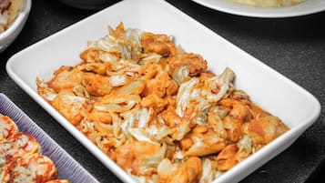 A white rectangular dish filled with a chicken and cabbage casserole, surrounded by other dishes on a dark countertop.