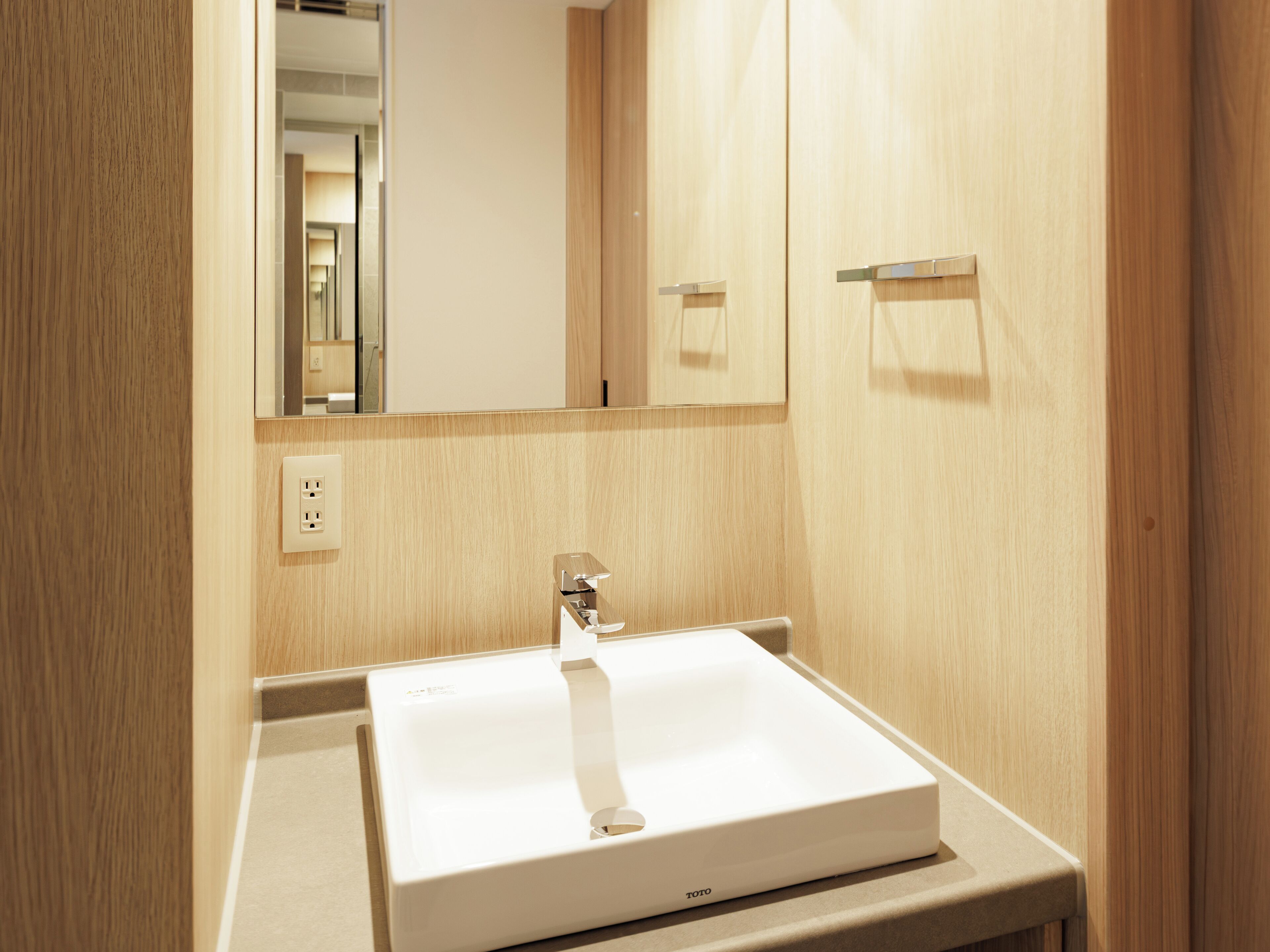 A bathroom with a white sink, a mirror, and wooden walls.