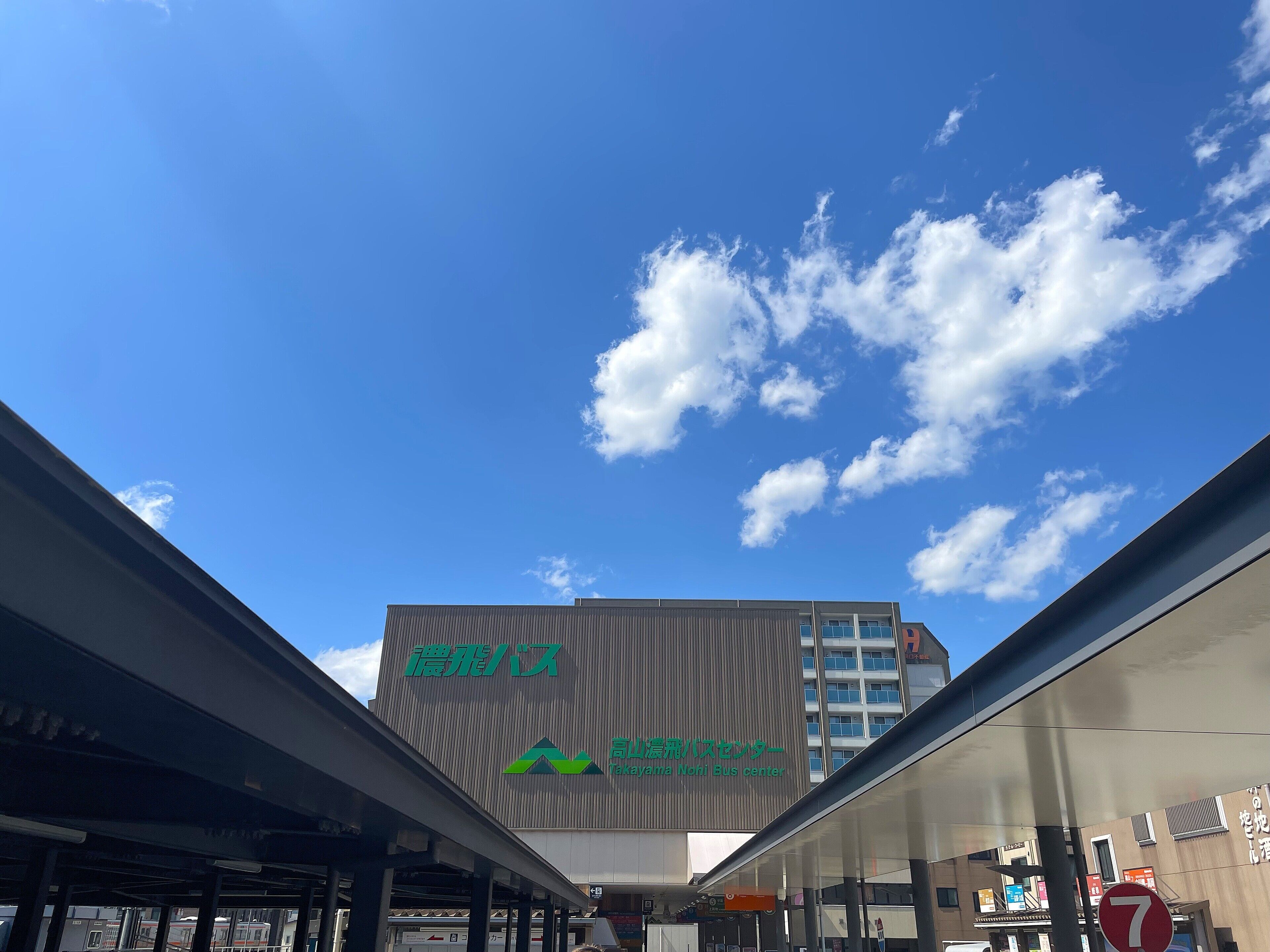 A bus station with a clear blue sky and clouds.