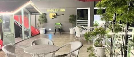 An outdoor patio area with wicker furniture, a potted plant, and a sign reading "Hadley Inn".