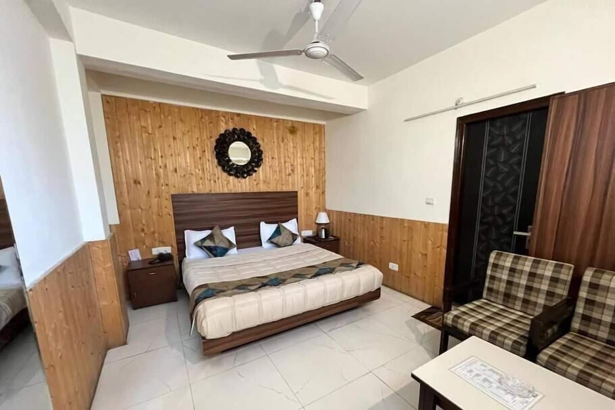 Un dormitorio ordenado con cabecera de madera, cama con colcha, mesita de noche, una silla y una mesa con un menú.