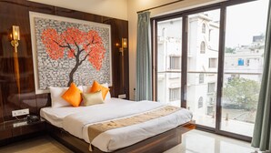 Ein modernes Schlafzimmer mit einem großen Bett, Blick auf die Stadt und einem gerahmten Kunstwerk an der Wand.