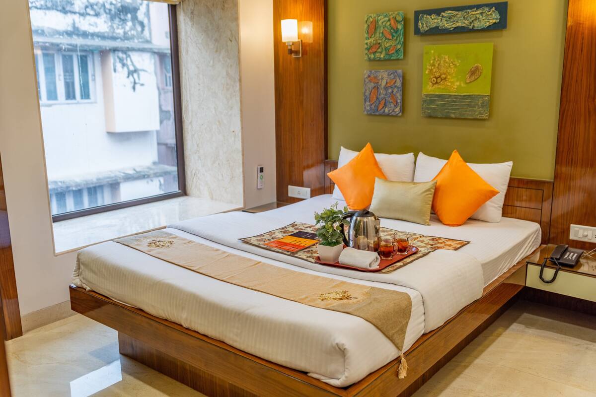 A double bed with a wooden frame, a bedside table with a phone, and artwork on the wall.