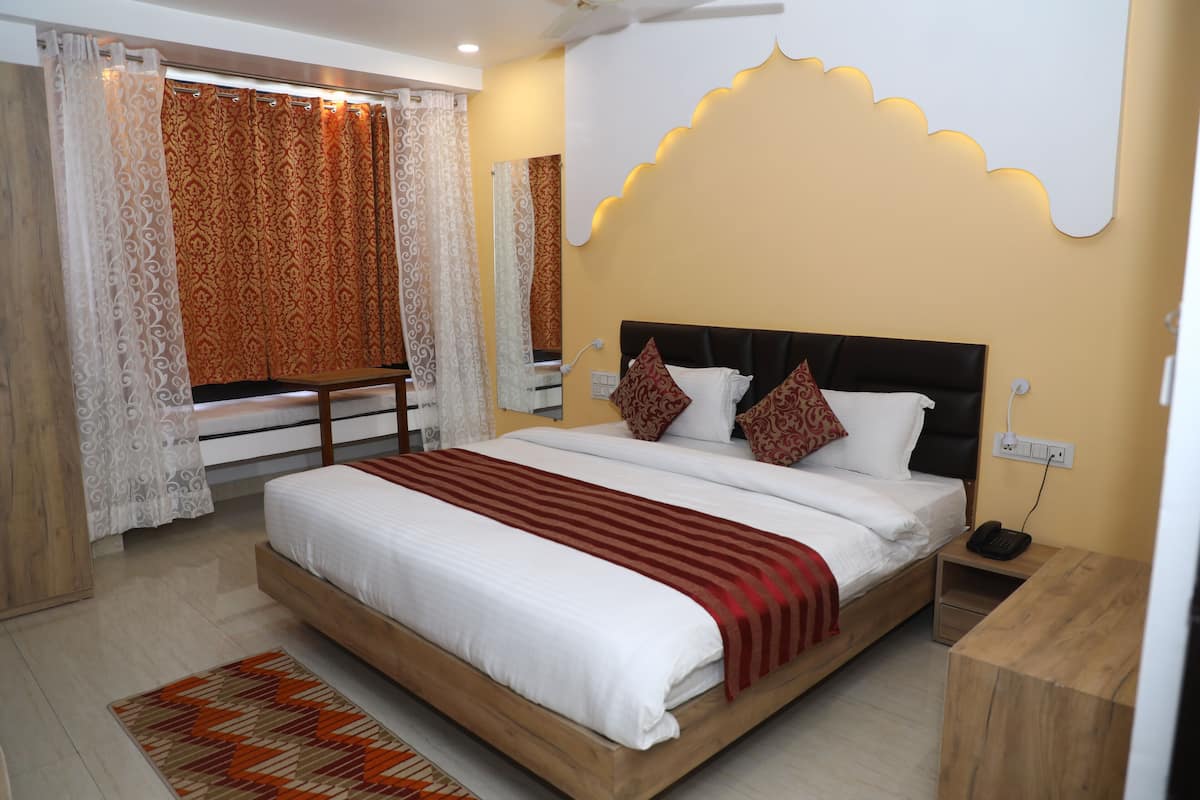 A bedroom with a large bed, a wooden nightstand, a bedside table, and a mirror on the wall.