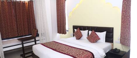 A hotel room with a large bed, a bedside table, a desk, and a ceiling fan.