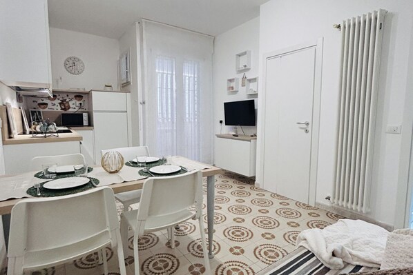 A compact kitchen with a microwave, a clock, and a TV on a stand. - Angiolieri Flexrent - Abyssinia (Riccione)