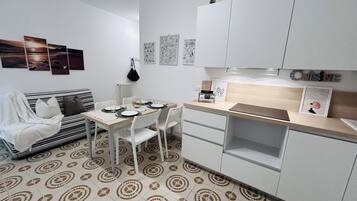 A compact living space with a dining area, kitchenette, and a sofa.