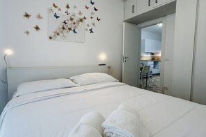A neatly made bed with white linens and a pair of folded towels on it. - Angiolieri Flexrent - Abyssinia (Riccione)