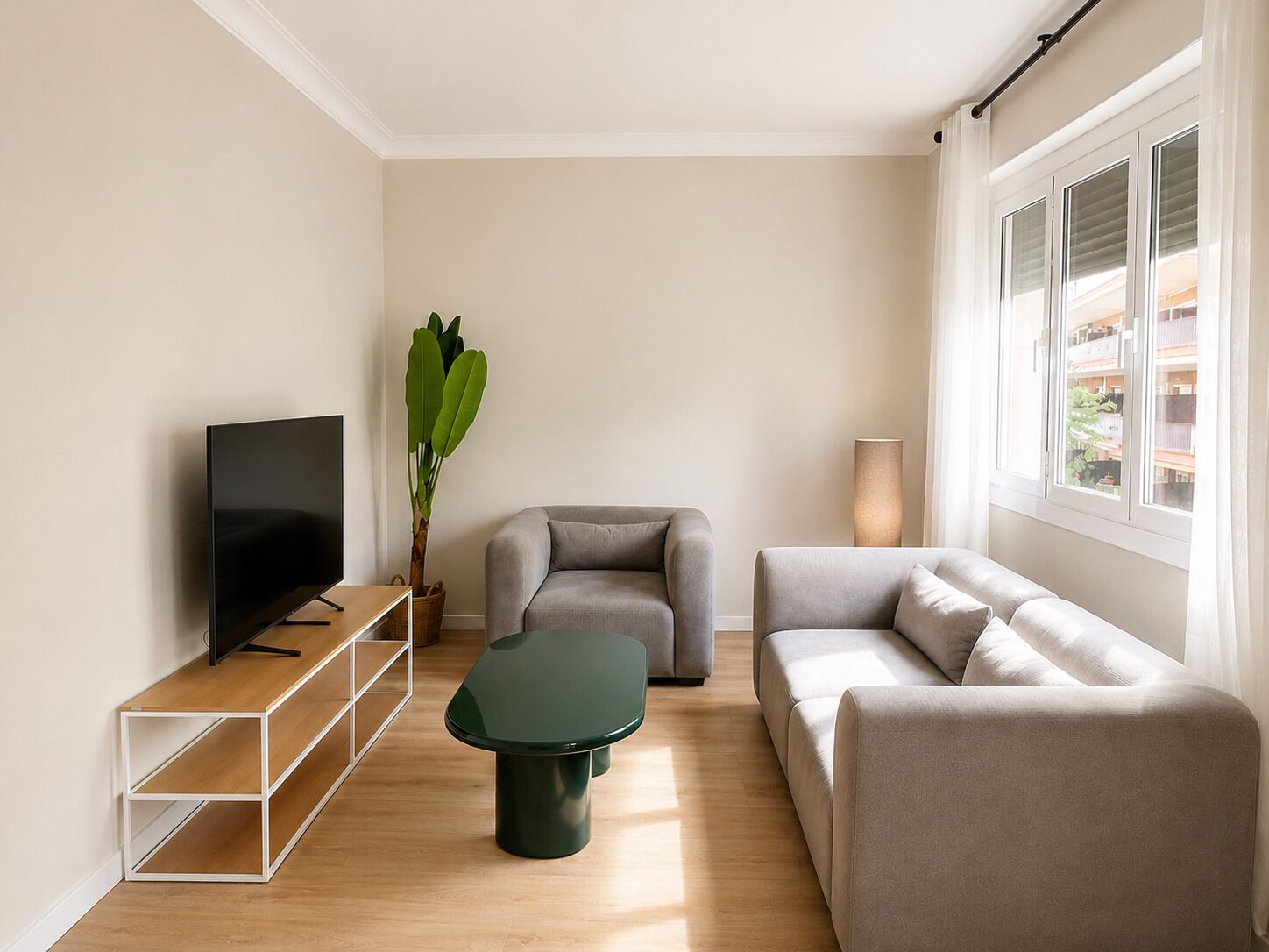 A modern living room with a flat-screen TV, two sofas, a coffee table, and a potted plant.