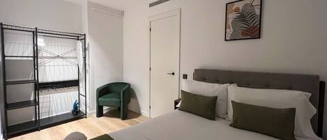 A bedroom with a bed, a green chair, a wardrobe, and a door.