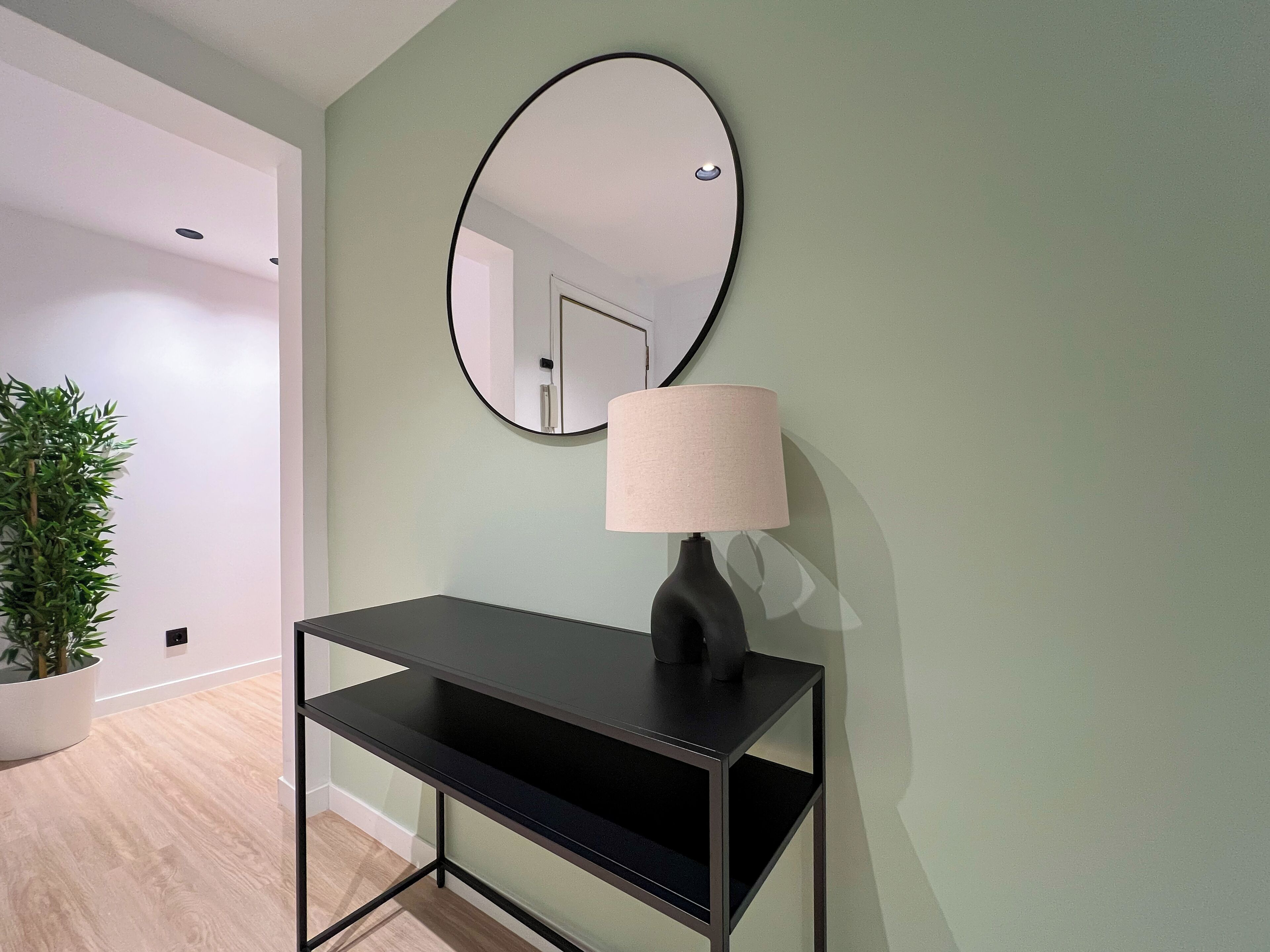A modern room with a black console table, a round mirror, and a lamp.